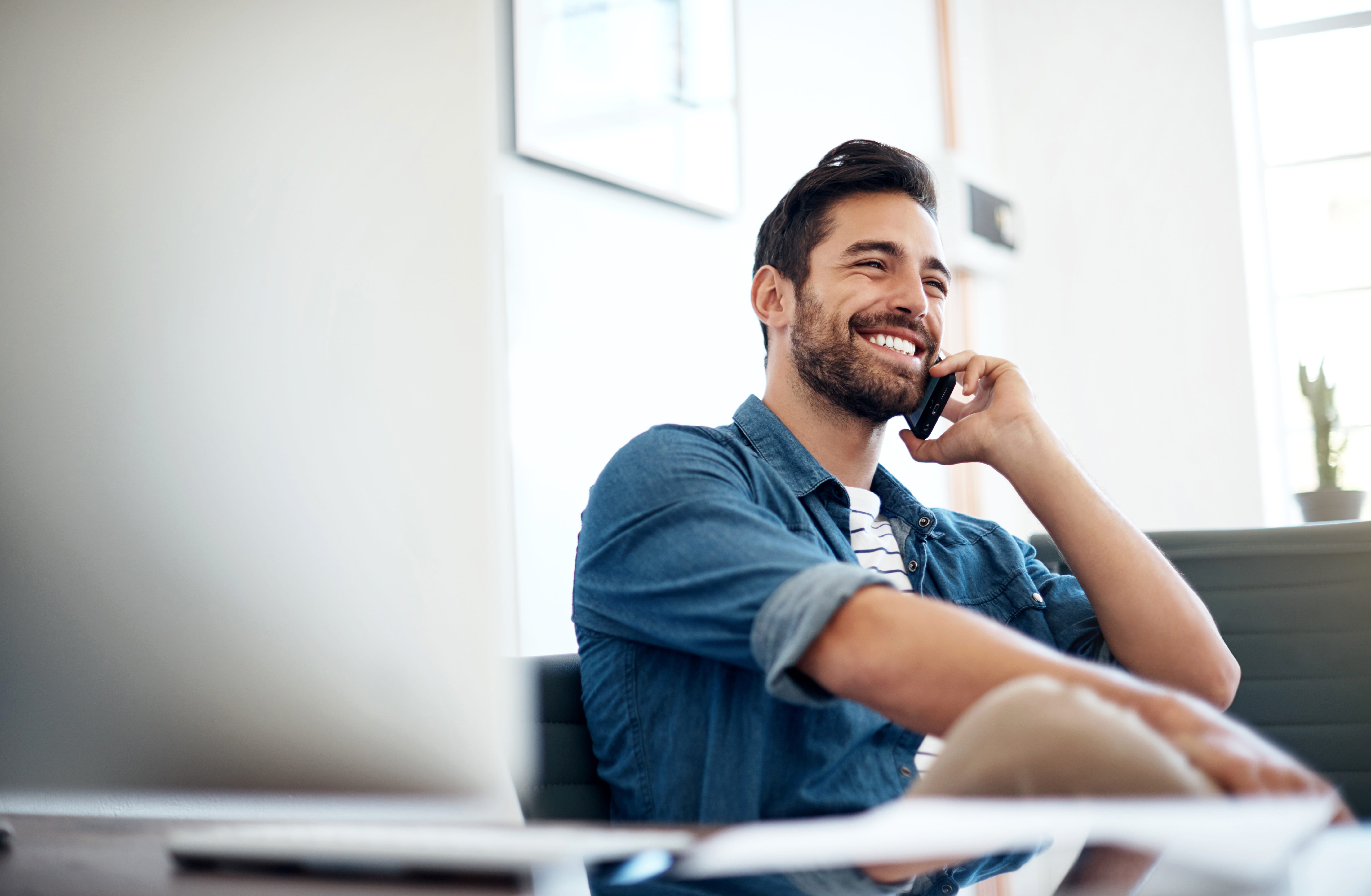 Man sitting and smiling while talking on his phone
